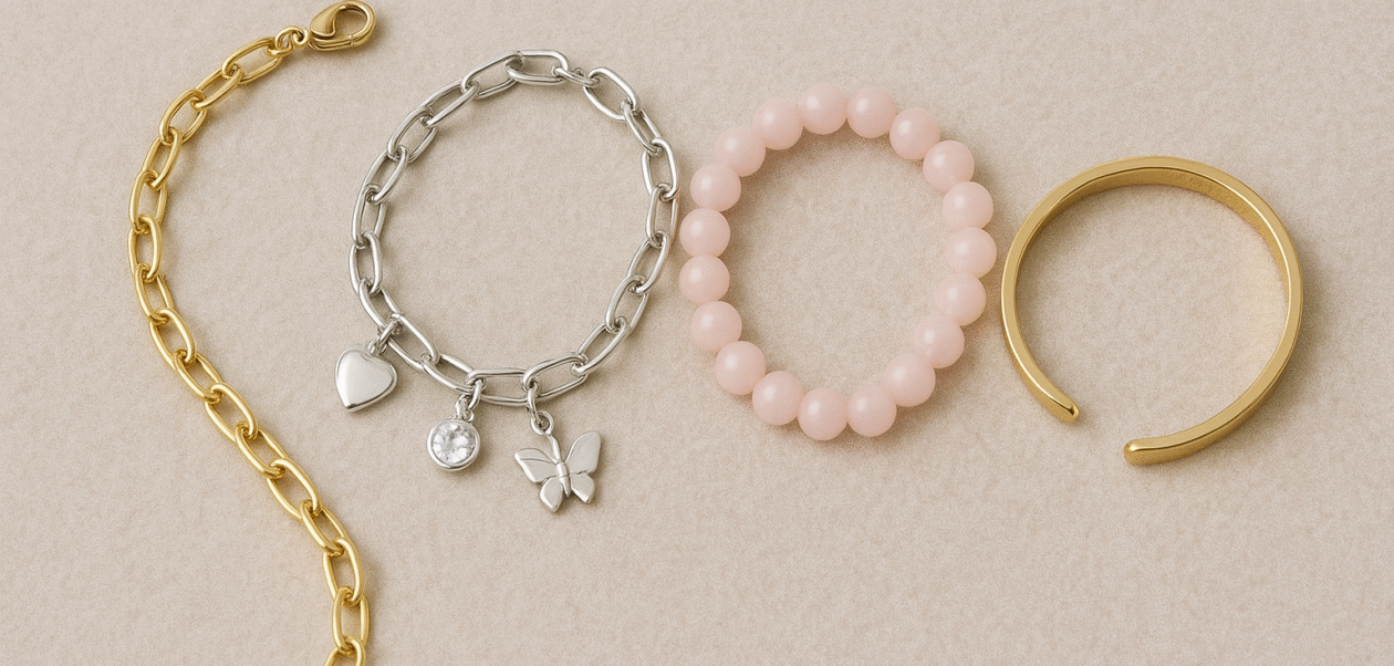 A collection of four stylish bracelets for girls displayed on a beige background, including a gold chain bracelet, a silver charm bracelet with butterfly and heart charms, a pink beaded bracelet, and a sleek gold cuff bracelet.